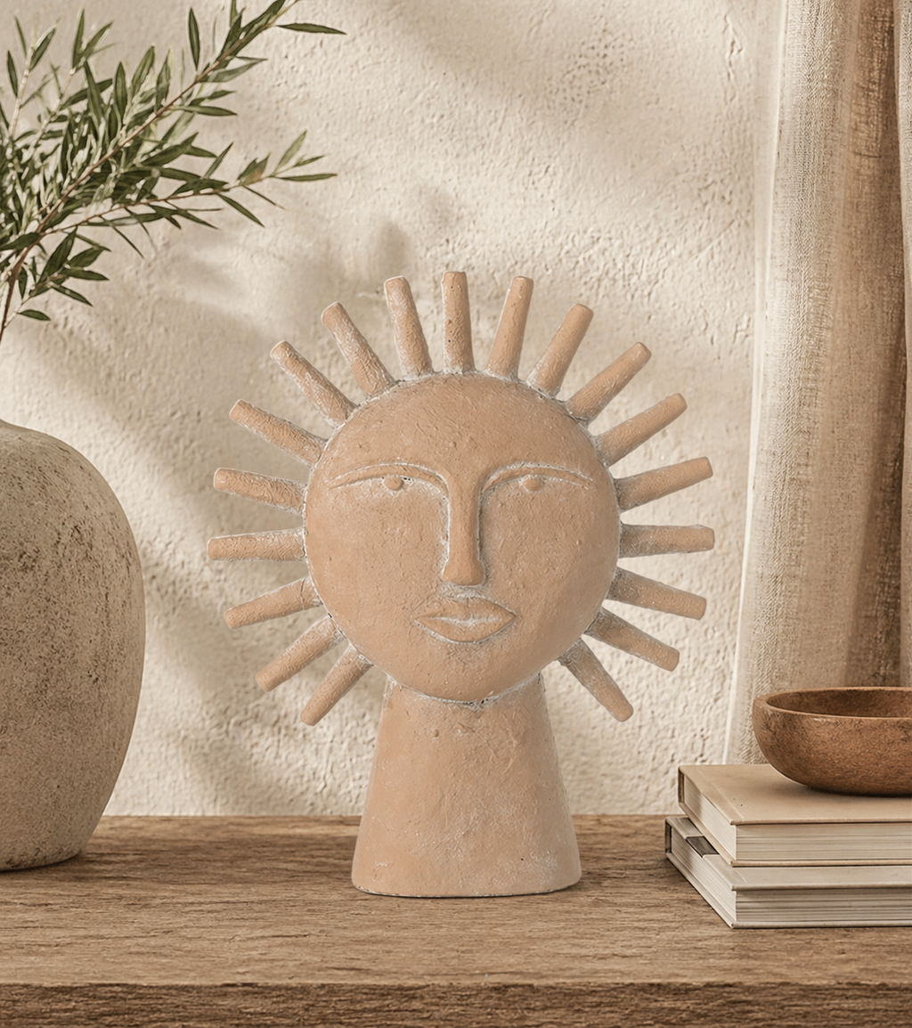 Ceramic sun-shaped face sculpture on a wooden surface with a neutral background