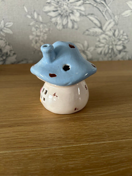 Ceramic mushroom shaped object on a wooden surface with floral-patterned fabric in the background.