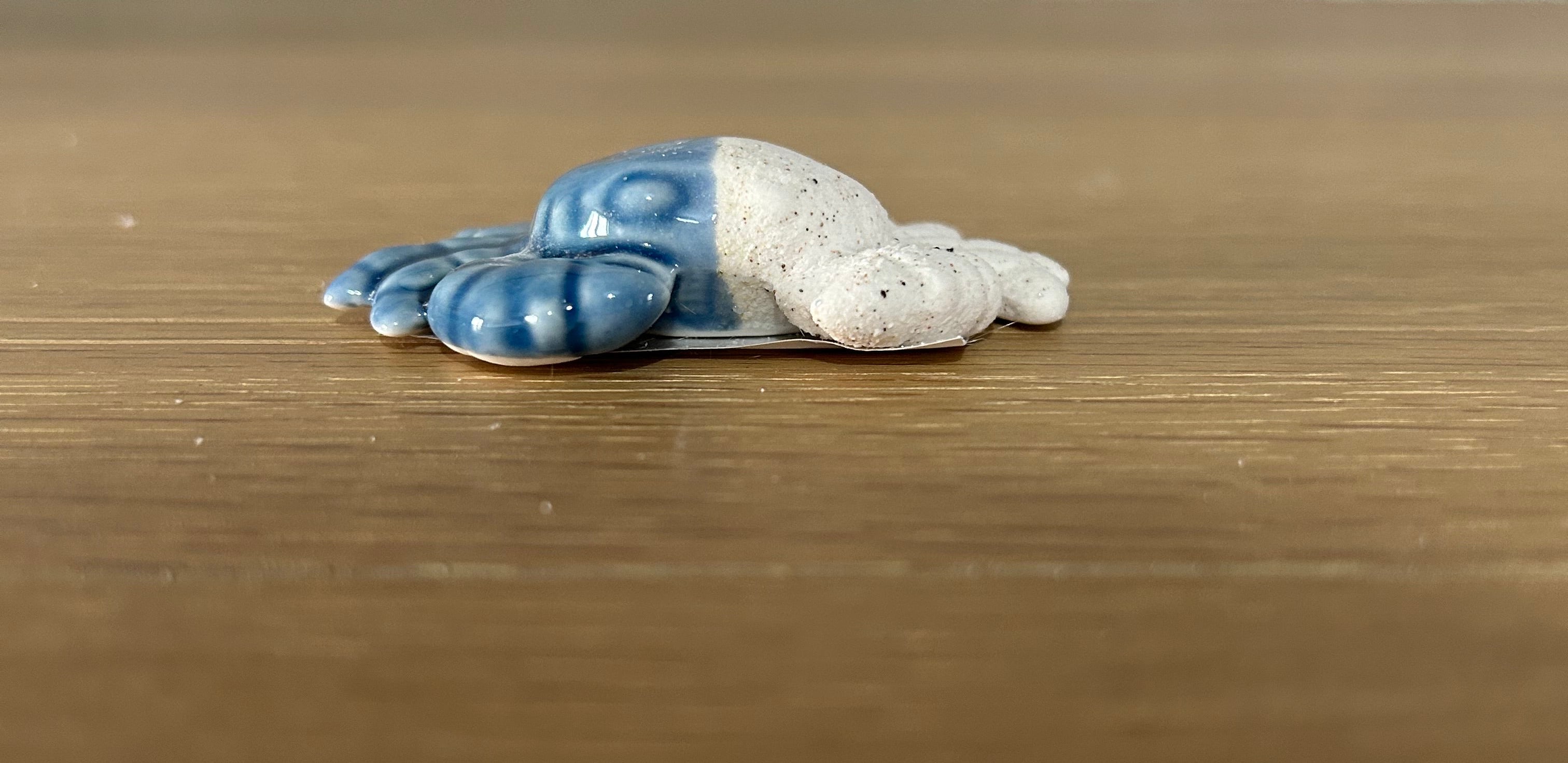 Small ceramic crab figurine with blue patterns on a wooden surface