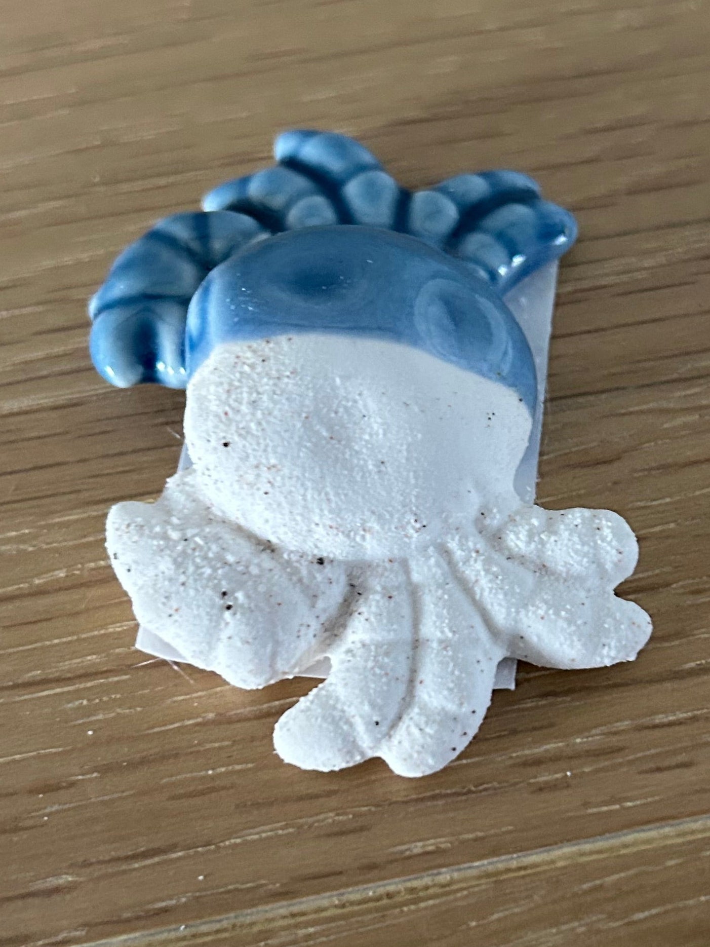 Blue and white ceramic fish-shaped object on a wooden surface
