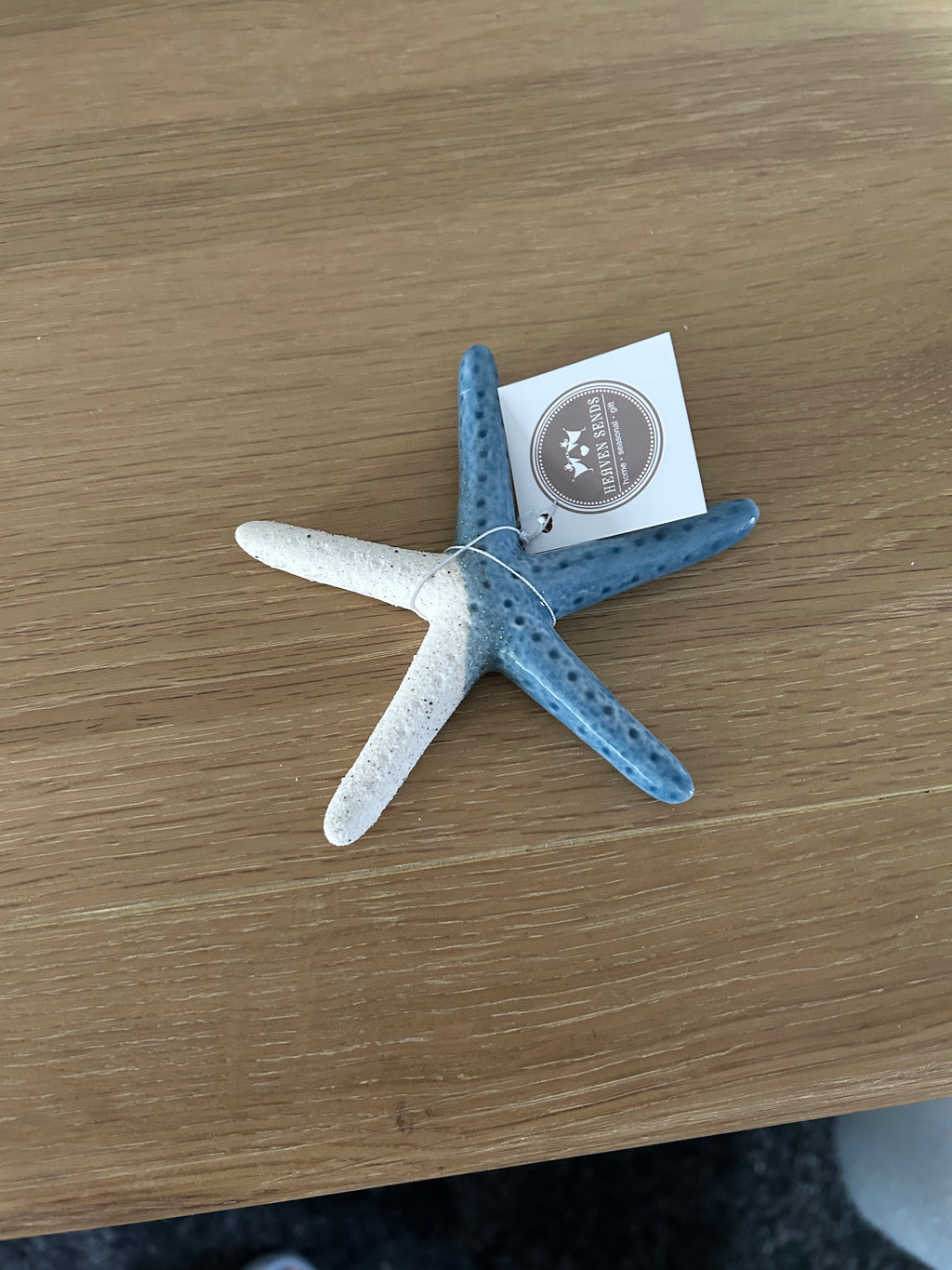 Blue starfish ornament on a wooden surface with a tag.