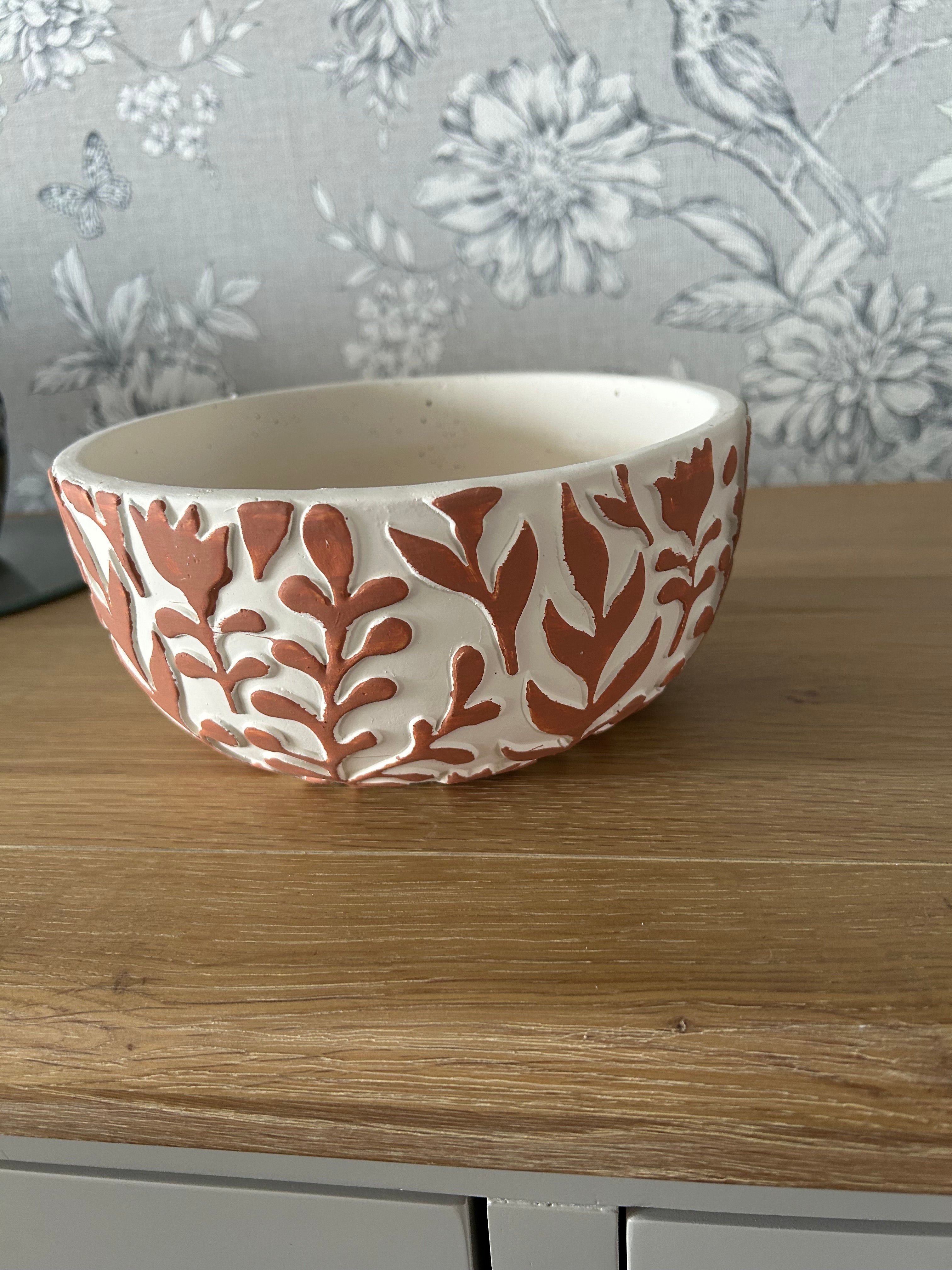 Decorative ceramic bowl with leaf pattern on a wooden surface