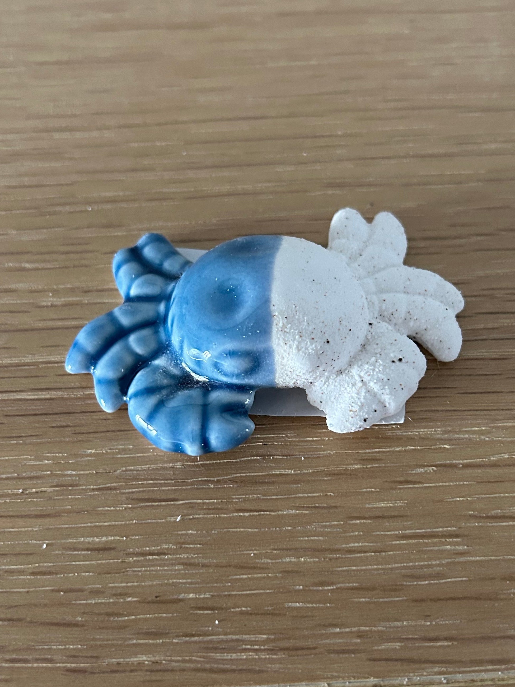 Blue and white crab-shaped object on a wooden surface