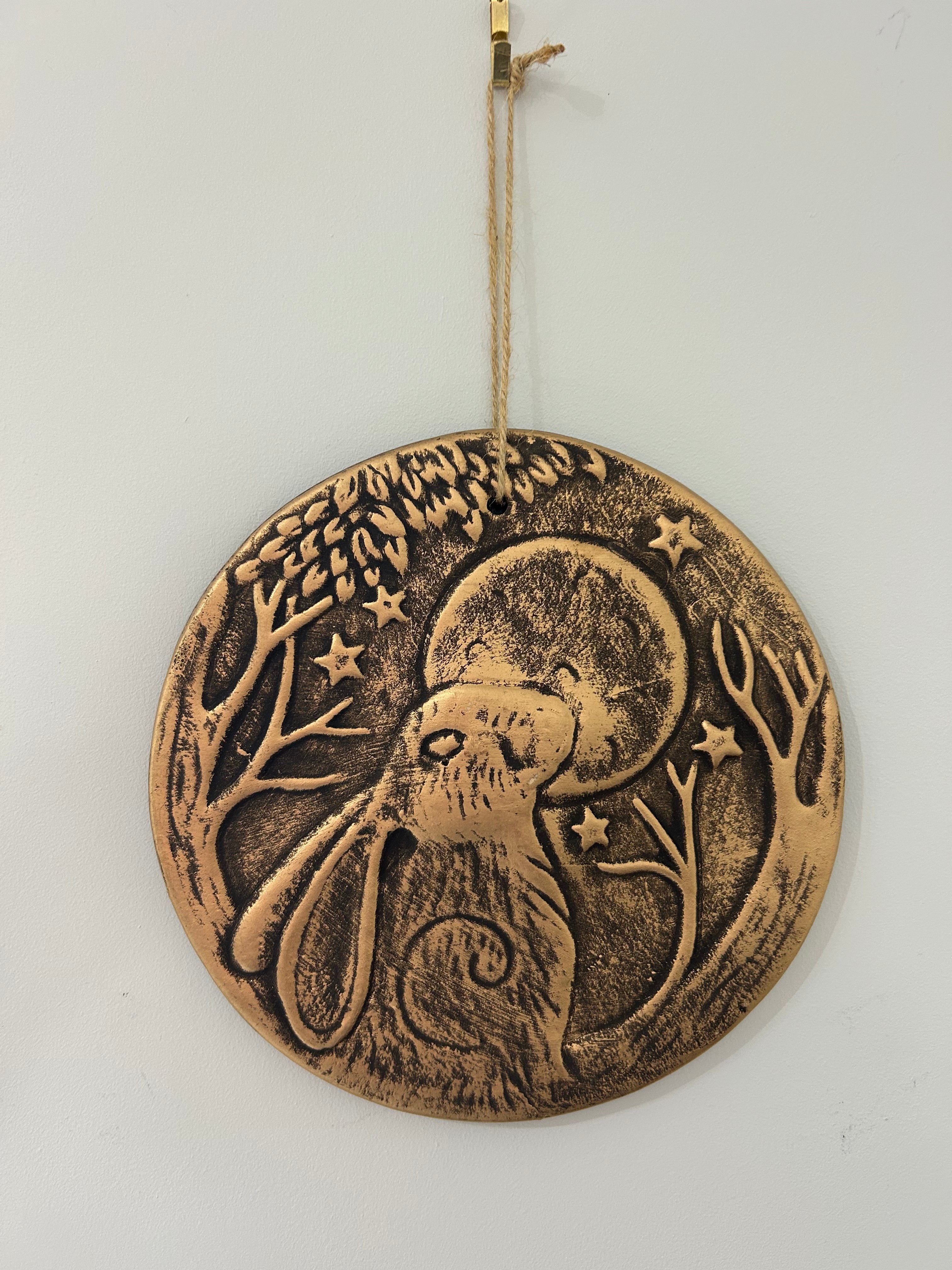 Bronze-colored decorative wall hanging with a hare and moon design 