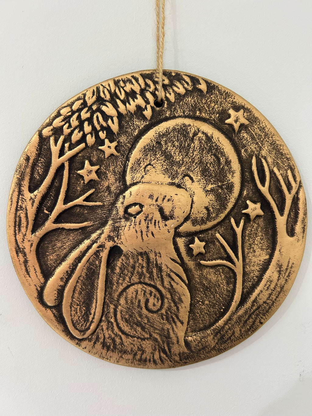 Bronze-colored decorative plaque with a rabbit and moon design on a white background